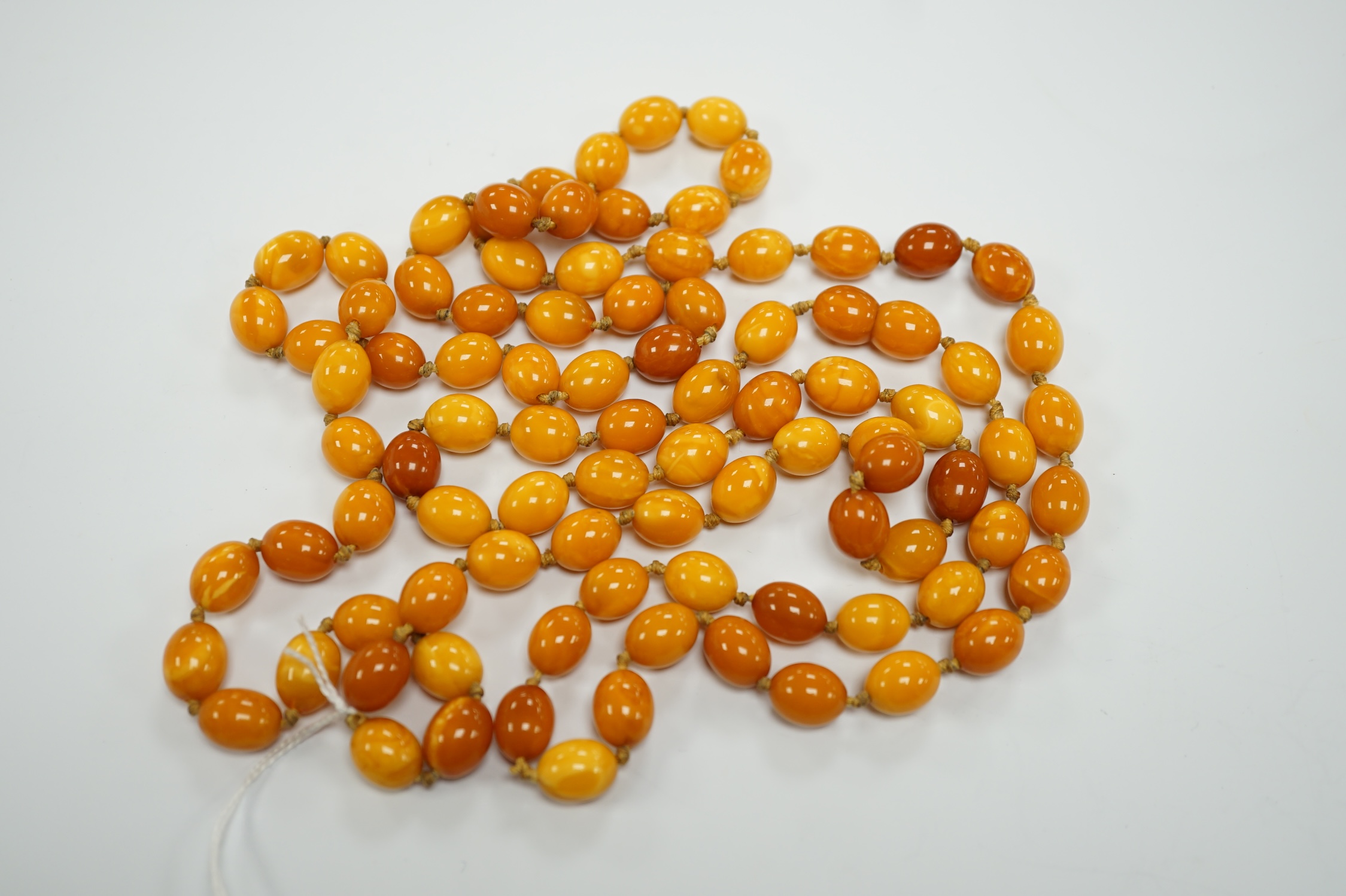 A long single strand oval amber bead necklace, 156cm, gross weight 89 grams.